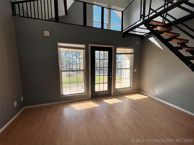 unfurnished living room with a high ceiling, wood finished floors, and a healthy amount of sunlight