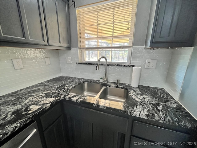 kitchen featuring gray cabinets, dark stone countertops, and a sink