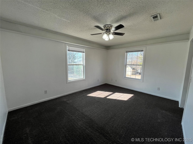 empty room with ceiling fan, a textured ceiling, visible vents, baseboards, and dark colored carpet