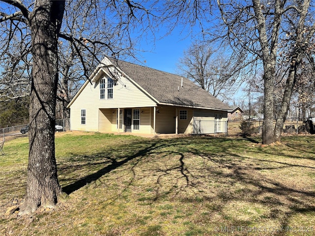 back of property with roof with shingles, a yard, and fence