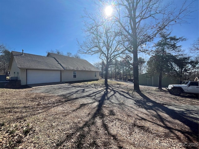 view of property exterior with driveway and roof with shingles