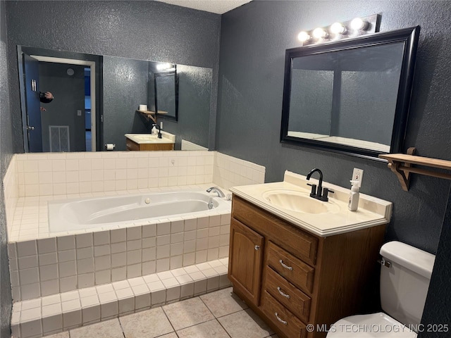 bathroom featuring a textured wall, toilet, tile patterned floors, vanity, and a bath