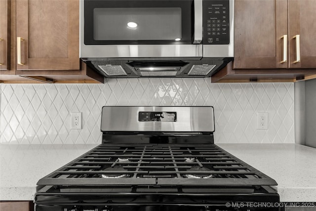 kitchen with stainless steel appliances, decorative backsplash, and light stone countertops