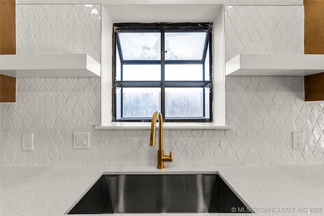 room details featuring light stone counters, a sink, and tasteful backsplash