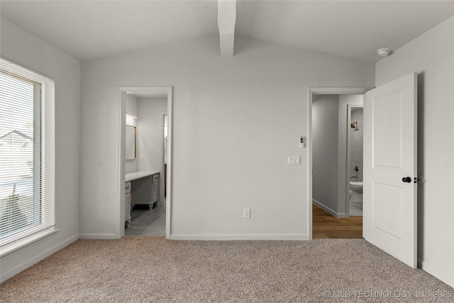 unfurnished bedroom with lofted ceiling, multiple windows, and light colored carpet