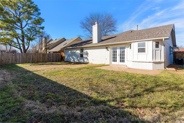 rear view of house with a yard, fence, and french doors