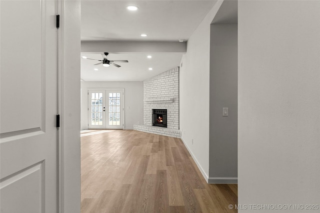 unfurnished living room featuring ceiling fan, light wood-style flooring, recessed lighting, baseboards, and a brick fireplace