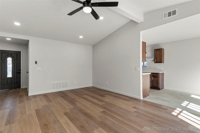 unfurnished living room with light wood-style floors, visible vents, and vaulted ceiling with beams