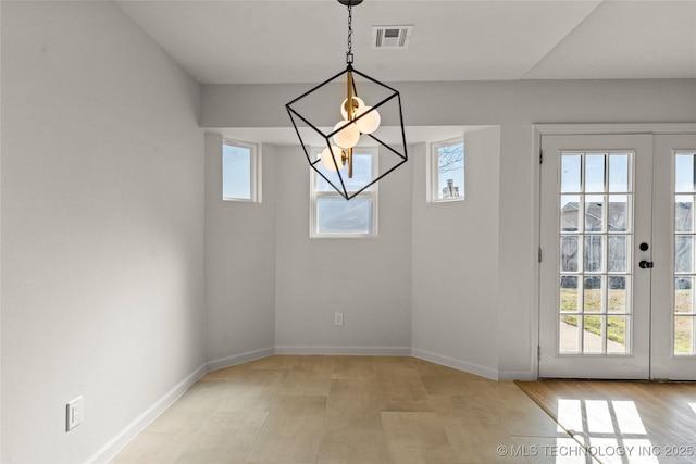 unfurnished dining area featuring light wood finished floors, baseboards, visible vents, and french doors