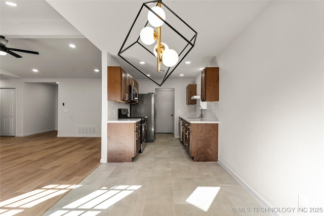 kitchen with stainless steel appliances, a sink, a ceiling fan, visible vents, and light countertops