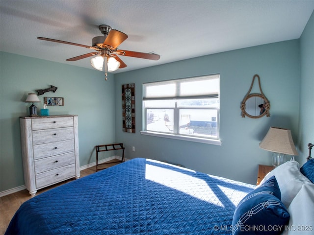 bedroom featuring ceiling fan, baseboards, and wood finished floors