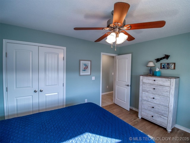 unfurnished bedroom featuring a ceiling fan, a closet, baseboards, and wood finished floors