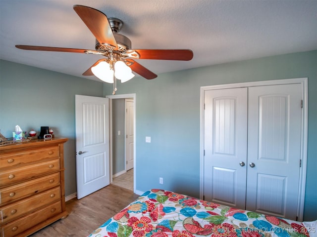 bedroom featuring light wood-style floors, a closet, baseboards, and a ceiling fan