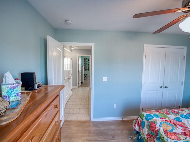 bedroom with a ceiling fan, baseboards, light wood finished floors, and a closet