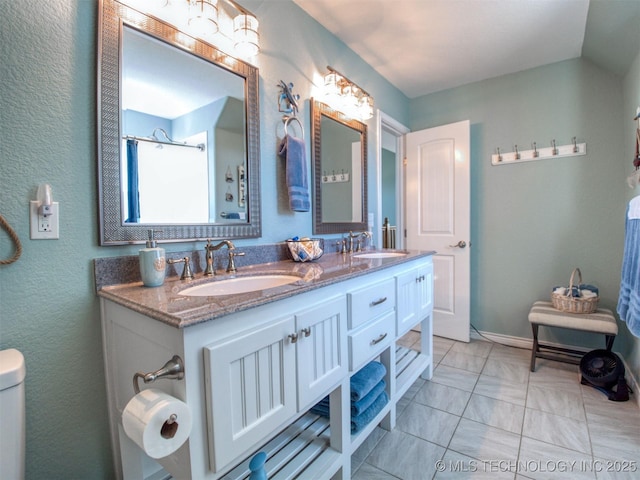 bathroom with lofted ceiling, double vanity, a sink, and baseboards