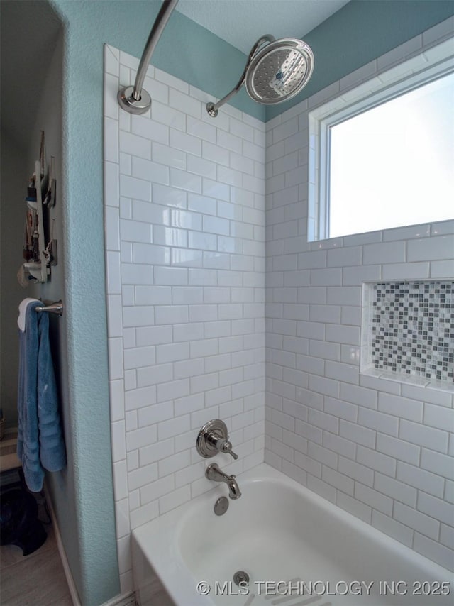 full bathroom with a textured wall and shower / bathtub combination