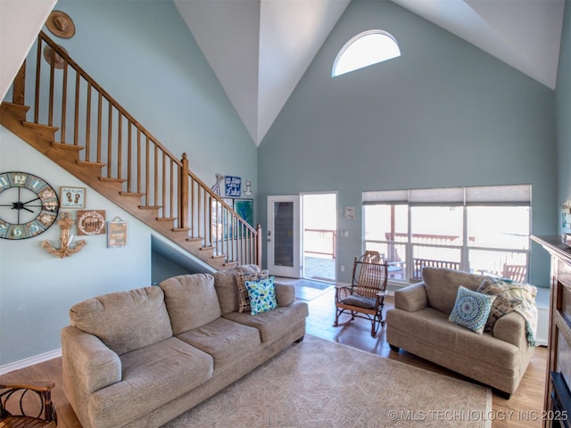 living area featuring stairs, high vaulted ceiling, baseboards, and wood finished floors