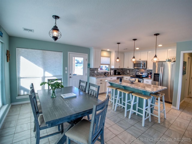 dining room with light tile patterned floors, visible vents, and baseboards