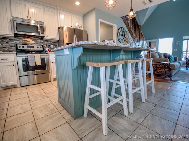 kitchen with pendant lighting, stainless steel appliances, a breakfast bar, and white cabinets