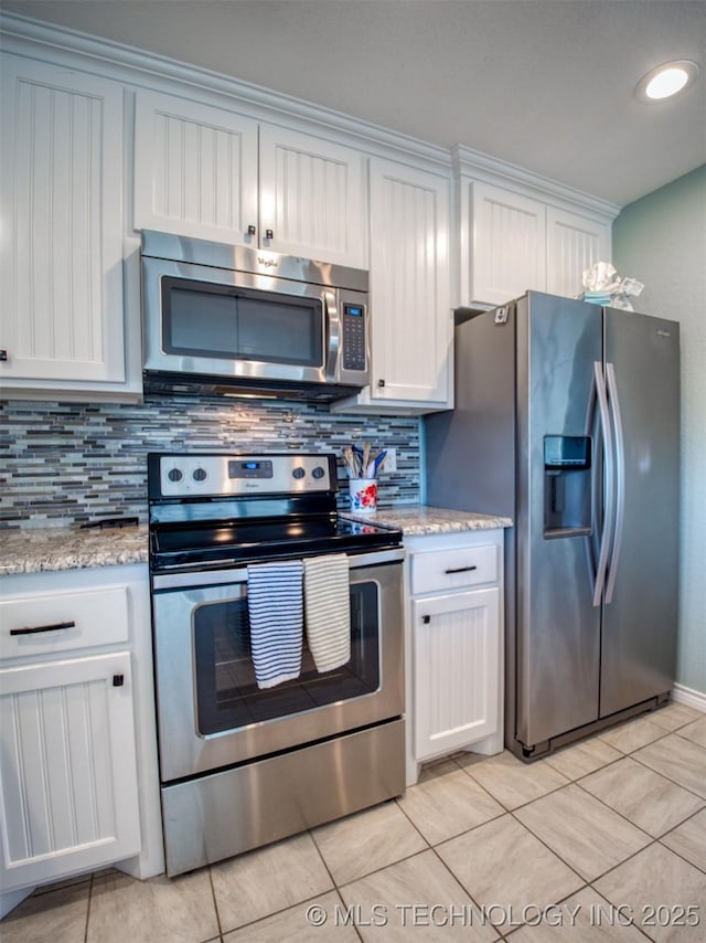 kitchen featuring stainless steel appliances, white cabinets, light stone counters, and tasteful backsplash