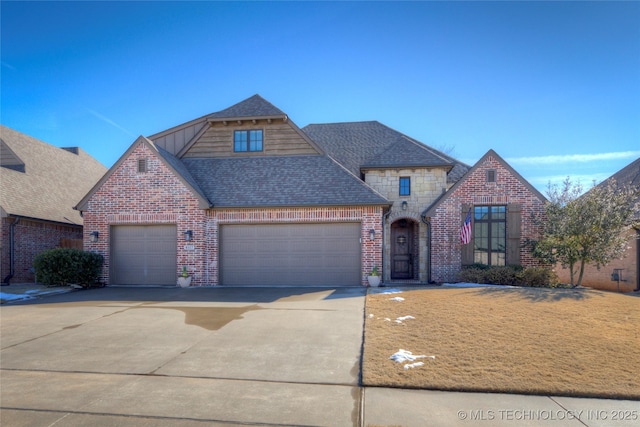 view of front facade with concrete driveway, stone siding, roof with shingles, an attached garage, and brick siding