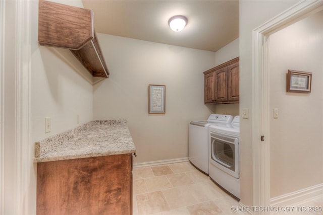 clothes washing area with cabinet space, washing machine and clothes dryer, and baseboards