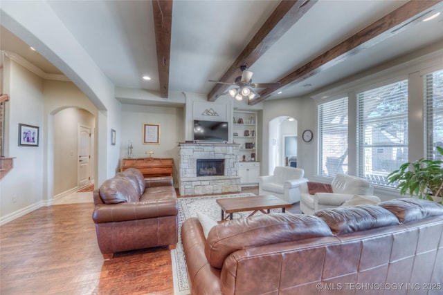 living area featuring baseboards, a fireplace, arched walkways, and wood finished floors