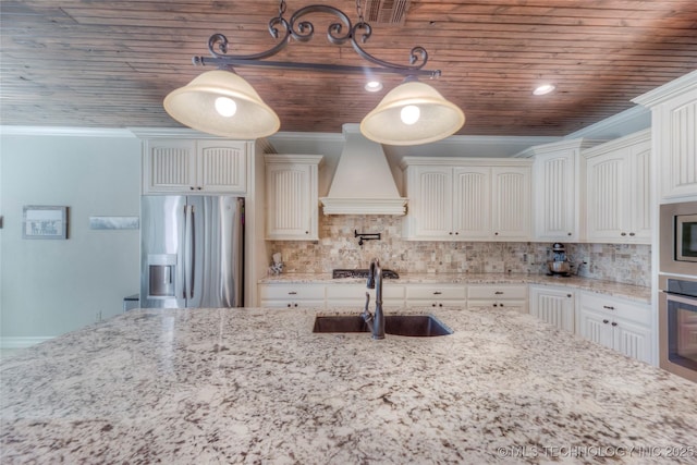 kitchen with custom range hood, stainless steel appliances, a sink, and pendant lighting