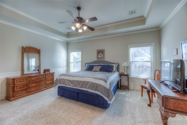 carpeted bedroom with a wainscoted wall, visible vents, a raised ceiling, and crown molding