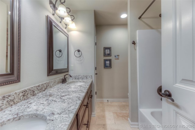 full bathroom featuring double vanity, baseboards, a sink, and shower / bathtub combination