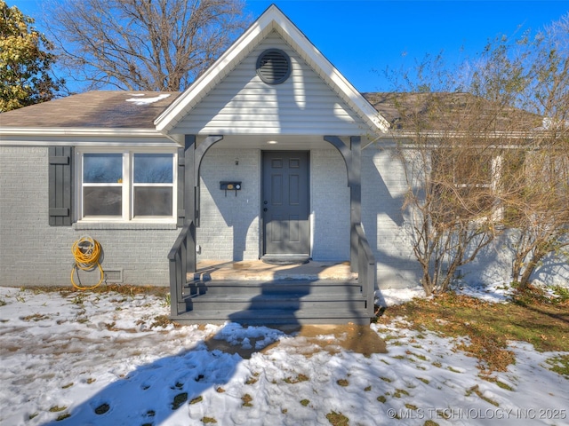 view of front of property with a shingled roof and brick siding