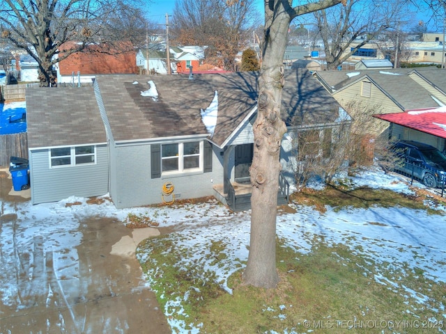 view of snow covered exterior with brick siding and a shingled roof