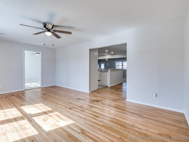 spare room featuring visible vents, ceiling fan, light wood-style flooring, and baseboards