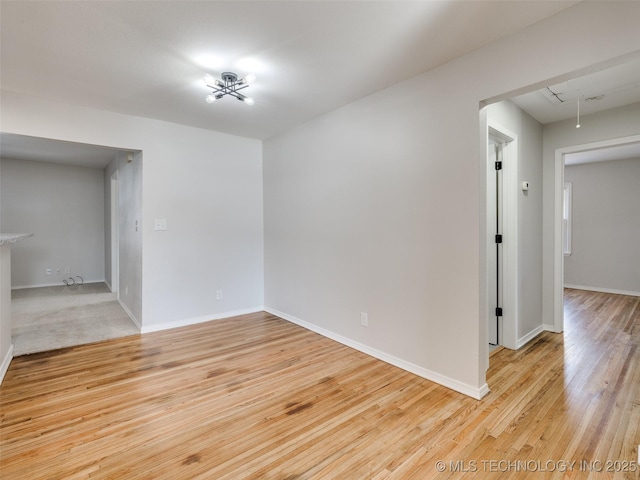 unfurnished room with attic access, light wood-style floors, and baseboards