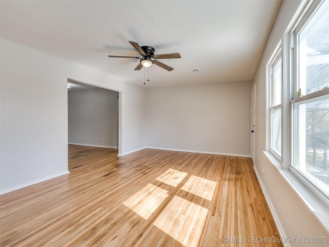 empty room with baseboards, ceiling fan, visible vents, and light wood-style floors