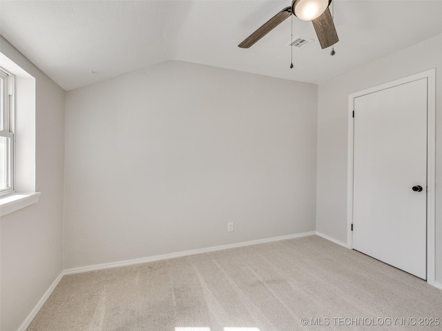 empty room featuring lofted ceiling, light colored carpet, visible vents, and baseboards