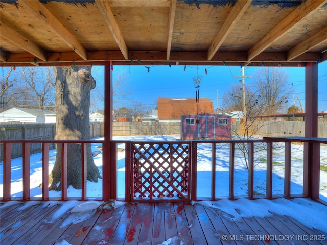 snow covered deck with a fenced backyard