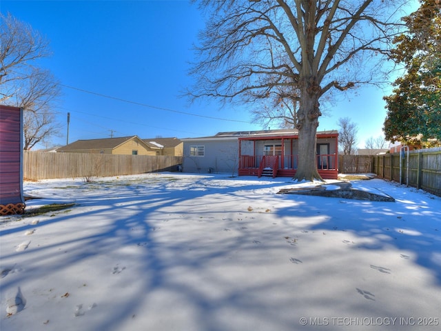 snow covered house featuring covered porch and fence private yard