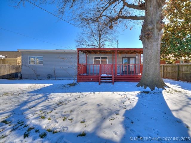 snow covered house featuring fence