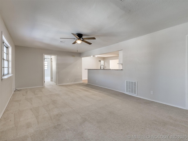 unfurnished room featuring a textured ceiling, visible vents, and light colored carpet