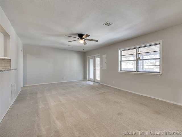 unfurnished living room featuring a textured ceiling, french doors, visible vents, and light colored carpet