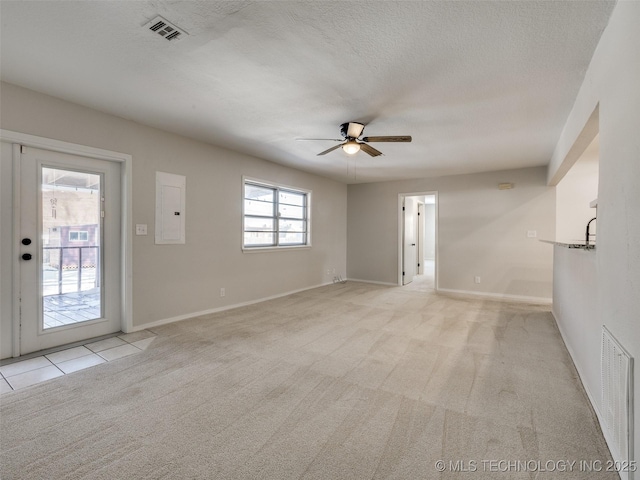 empty room with a textured ceiling, electric panel, visible vents, and light colored carpet