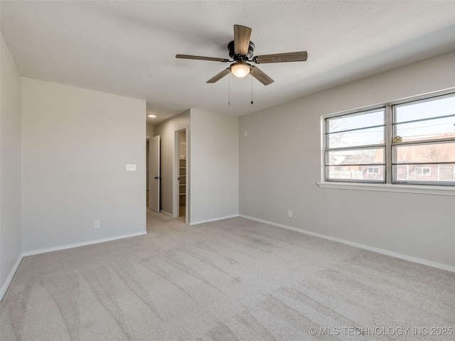 spare room with a textured ceiling, a ceiling fan, light colored carpet, and baseboards