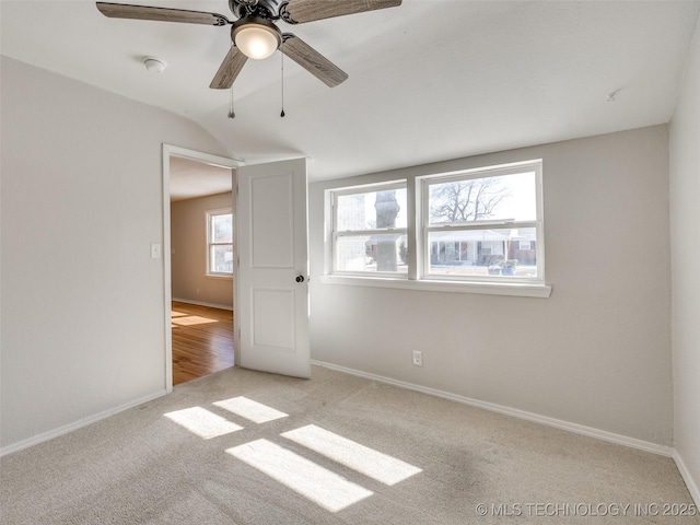 unfurnished bedroom featuring light carpet, ceiling fan, vaulted ceiling, and baseboards