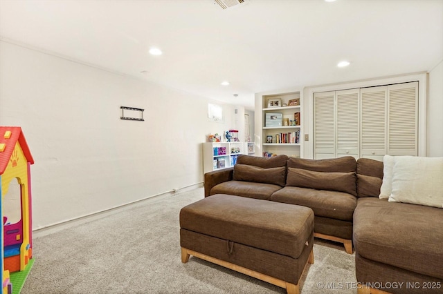 living room with built in shelves, recessed lighting, light colored carpet, and visible vents