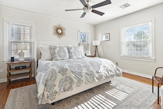 bedroom with wood finished floors, visible vents, and baseboards