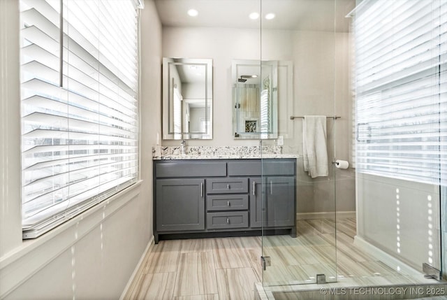 bathroom with recessed lighting, a sink, baseboards, double vanity, and a stall shower