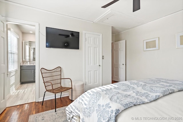 bedroom with attic access, baseboards, ensuite bath, ceiling fan, and dark wood-style flooring