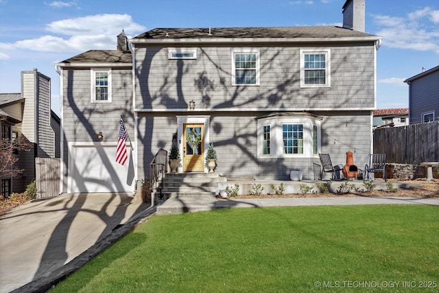 back of property featuring a chimney, a lawn, fence, and concrete driveway