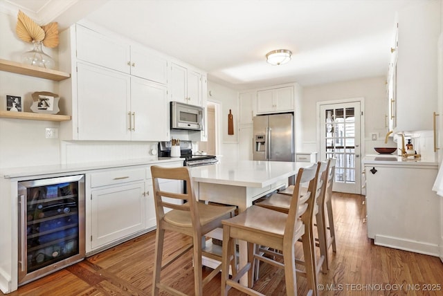 kitchen featuring beverage cooler, white cabinets, appliances with stainless steel finishes, light countertops, and open shelves